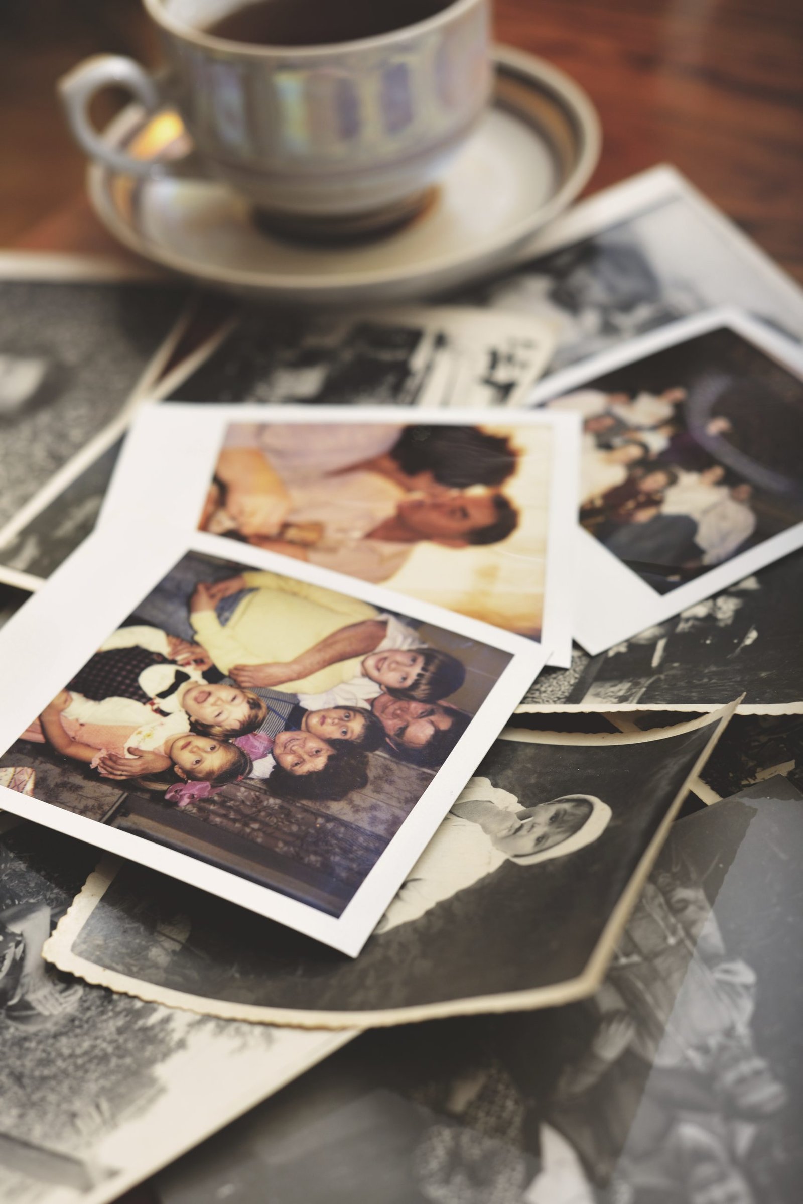 Pile of family photographs on table, next to tea cup